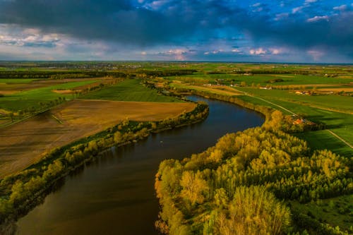 Aerial View of a River between Croplands in Summer 