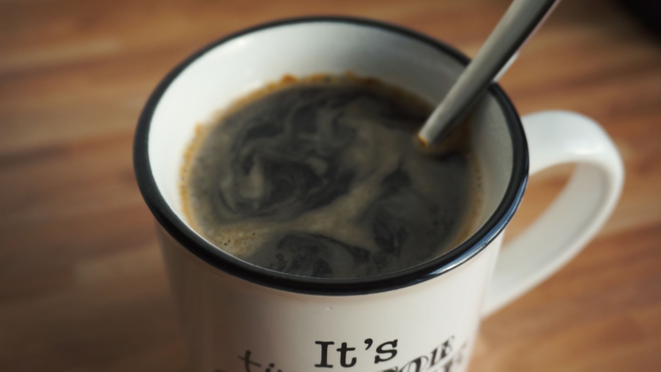 A close-up shot of hot black coffee in a white mug with a spoon, perfect for morning refreshment.