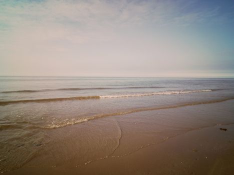 Peaceful ocean waves roll onto the sandy beach at Pensarn, Wales.