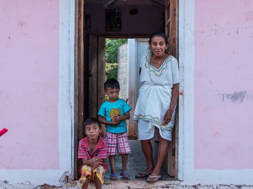 Free A woman with two children standing and sitting in a doorway in Maní, Mexico, showcasing local life. Stock Photo