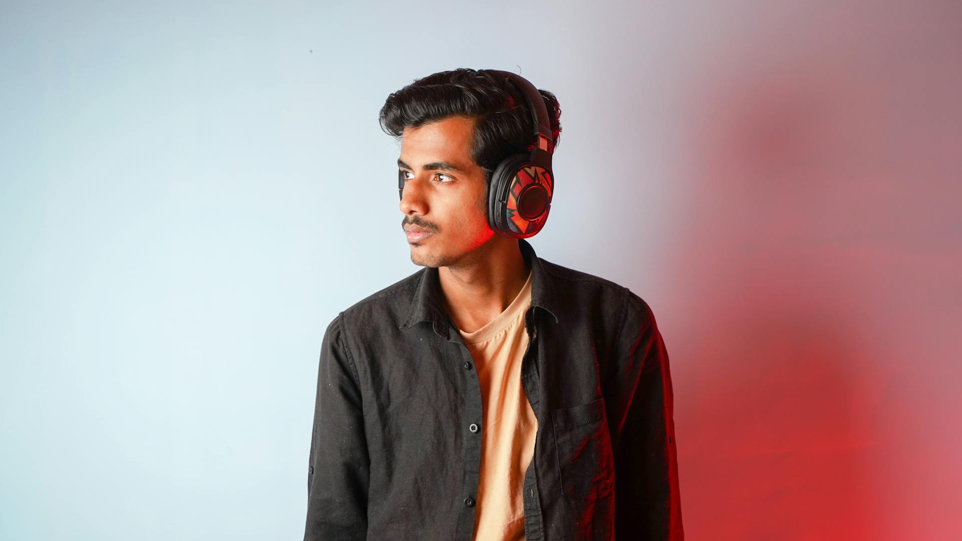 Young man in a studio wearing headphones with a colorful backdrop.