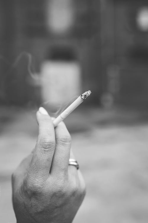 Grayscale Photography of Hand Holding Cigarette
