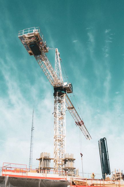 Photo by NITIN CHAUHAN A towering crane at a construction site reaching into a clear blue sky, symbolizing growth and progress.
