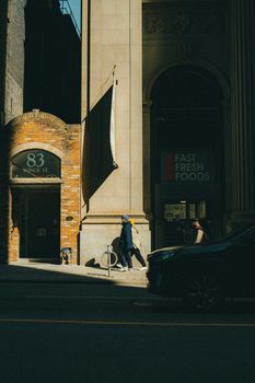 Street view with pedestrians passing by 83 Yonge St, Toronto, in a sunlit urban setting.