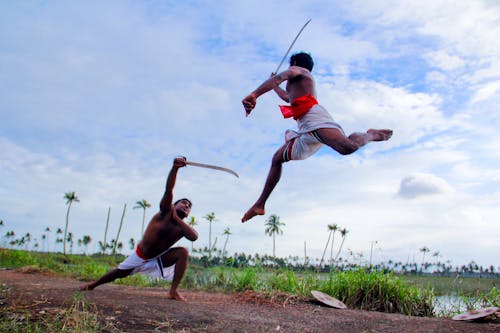 Free Two Man in White Shorts Fighting Using Sword during Daytime Stock Photo
