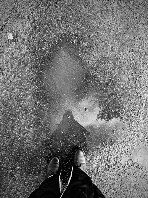 Person Standing on the Road over a Puddle 