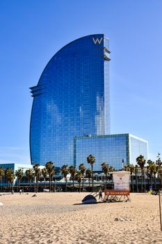 Iconic W Hotel in Barcelona overlooking sunlit sandy beach.