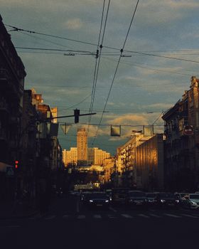 A vibrant urban street in Kyiv, Ukraine, featuring modern architecture and lively city traffic at dusk.