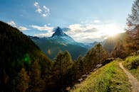 马特洪峰山顶的日出，在郁郁葱葱的绿植和晴朗蓝天的映衬下，景色格外壮美