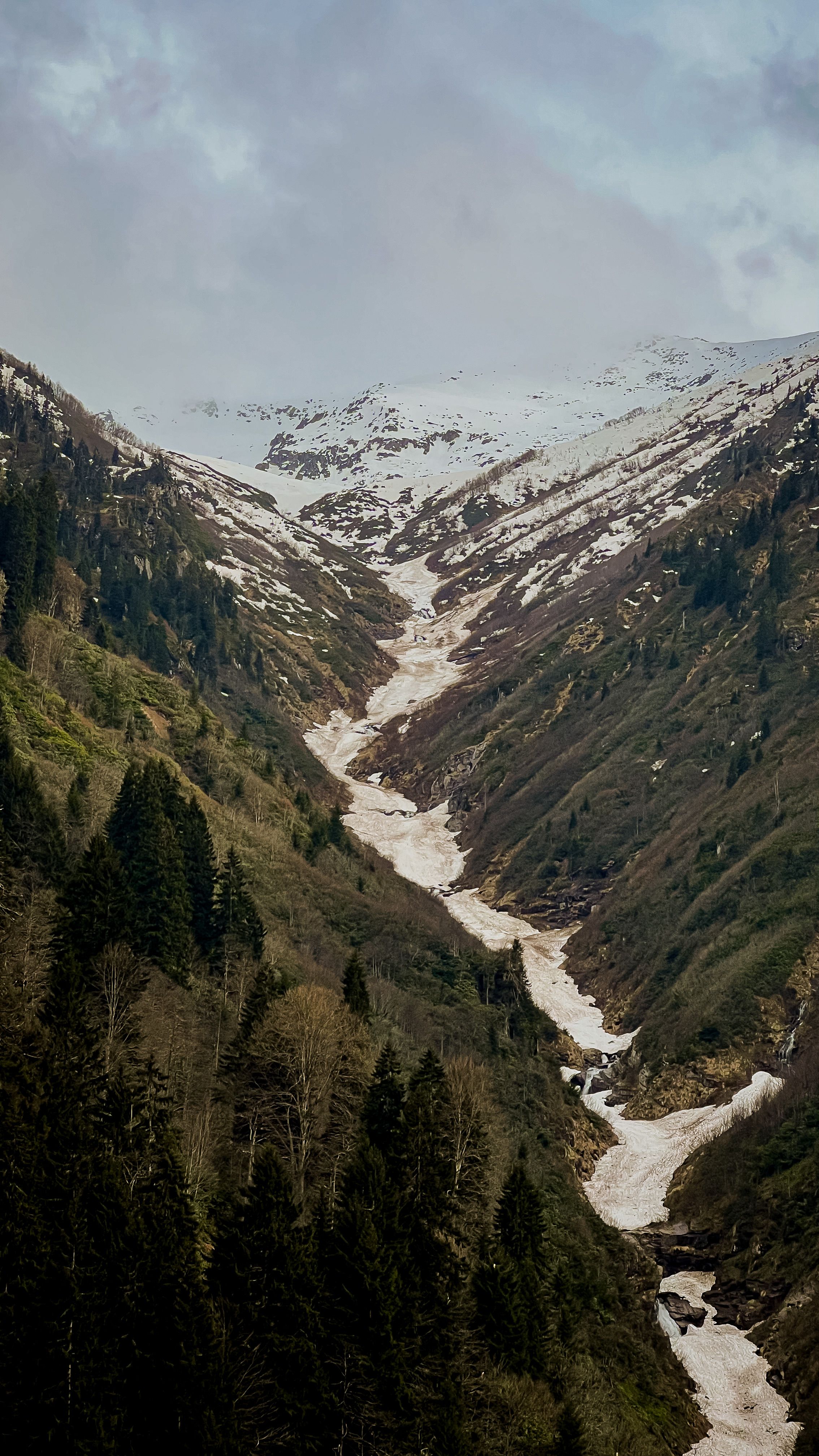 Stunning aerial view of a snow-dappled alpine valley transitioning from winter to spring.