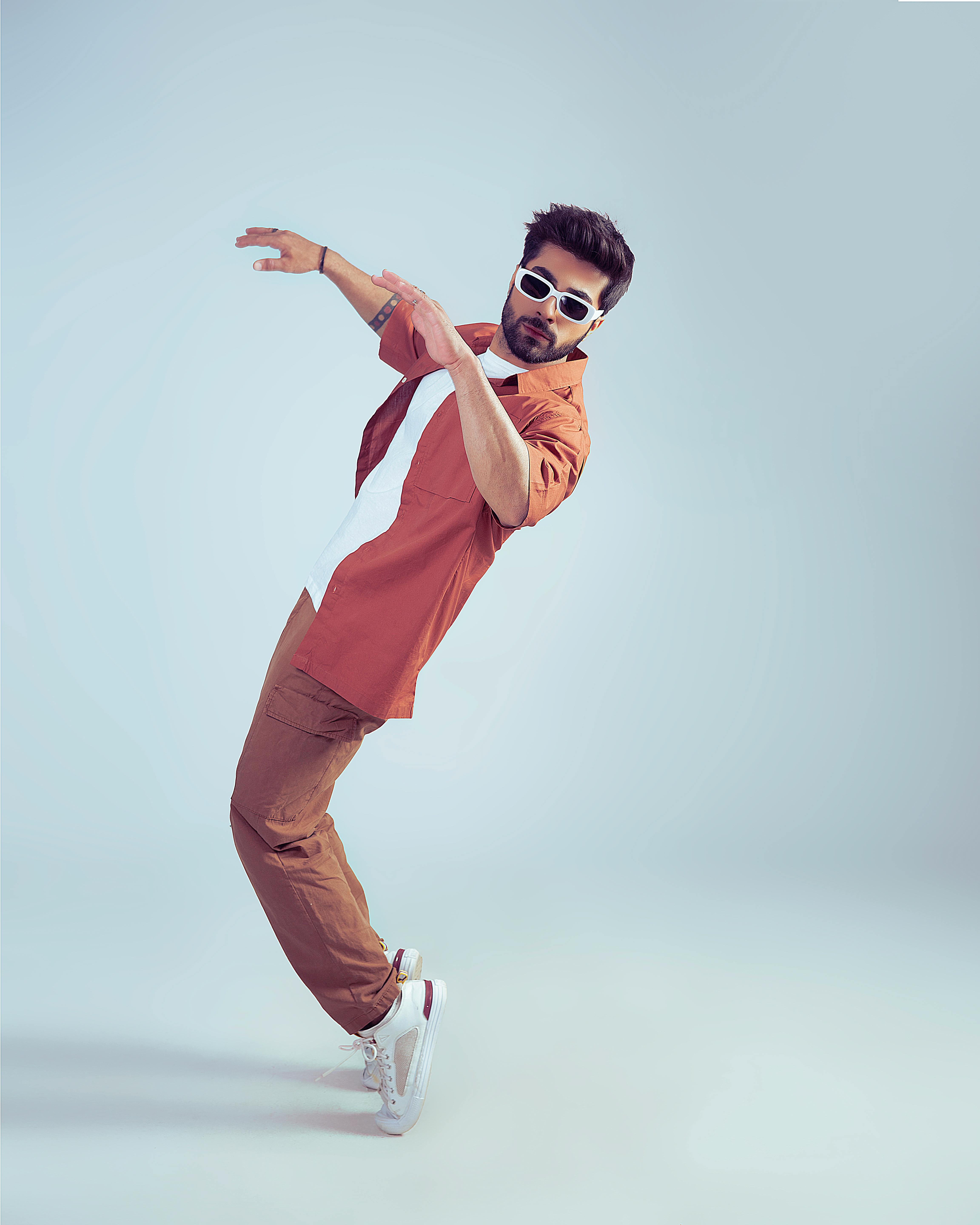 Stylish man in sunglasses striking a pose against a white background.