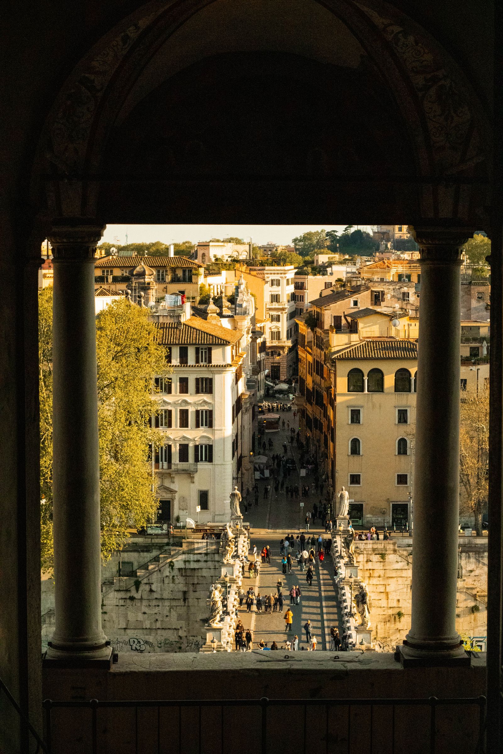 Ponte SantAngelo and Rome rooftops at golden hour from Castel SantAngelo