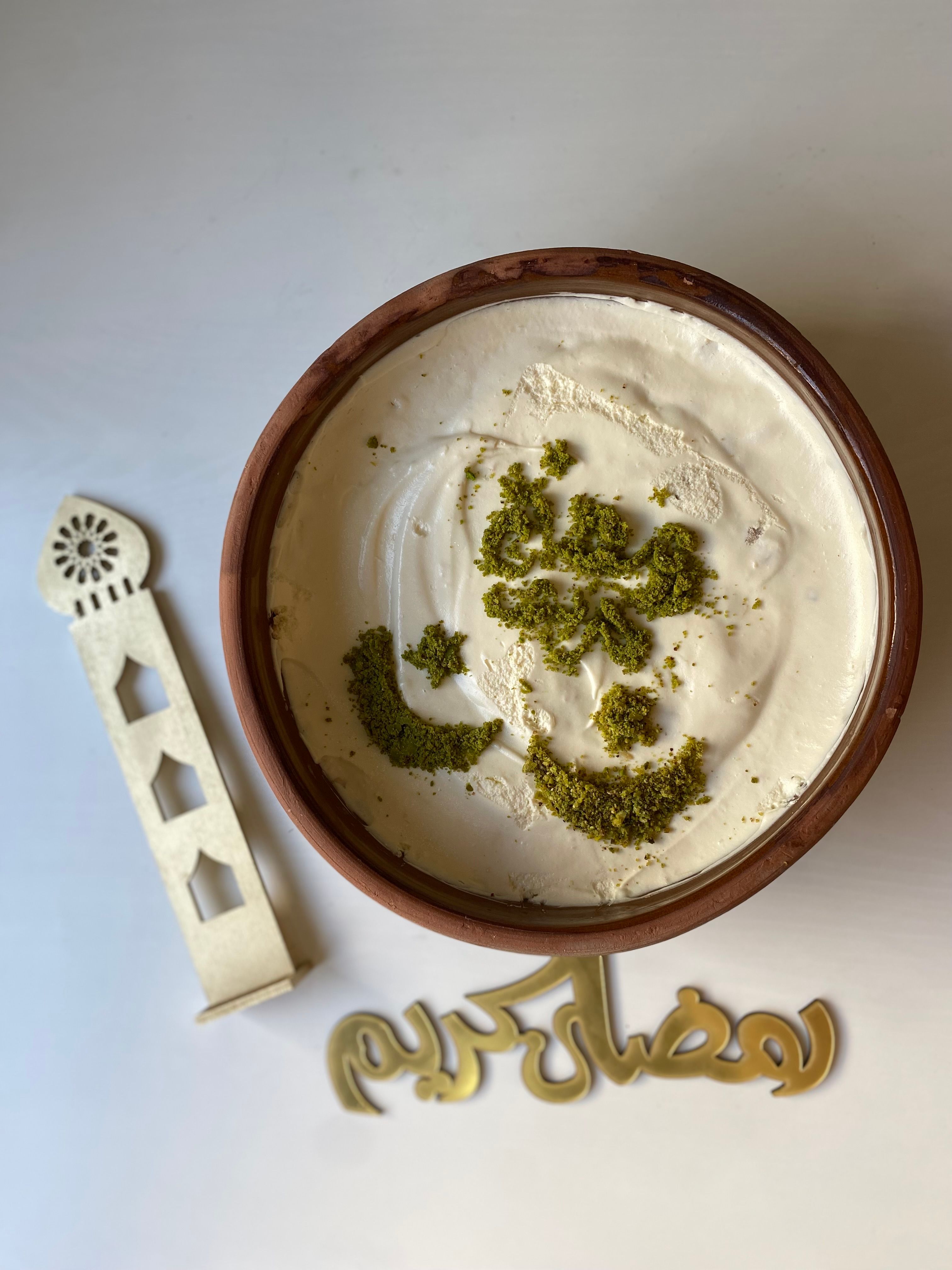 Top view of a creamy dessert with intricate pistachio design, perfect for festive occasions.