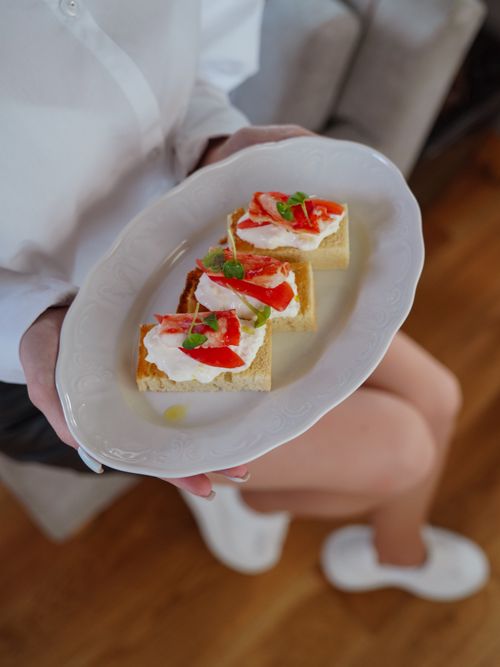 Free Plate of delicious bruschetta with fresh toppings held by a woman indoors. Stock Photo