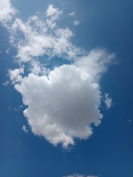 A single fluffy white cloud floating against a vibrant blue sky, creating a serene cloudscape.