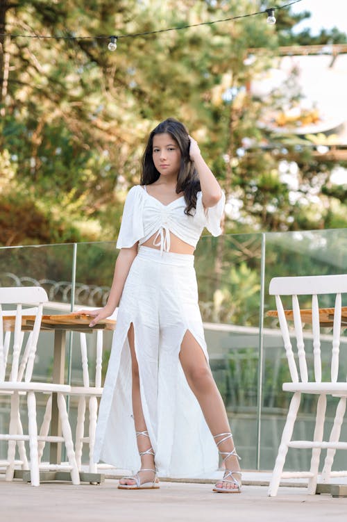 Young Brunette in a White Summer Outfit Posing Outdoors