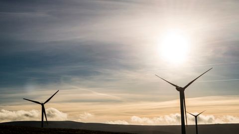 Silhouetted wind turbines generate renewable energy against a stunning sunrise sky.