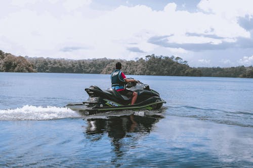 бесплатная Человек, едущий на зеленом гидроцикле на водоеме Стоковое фото