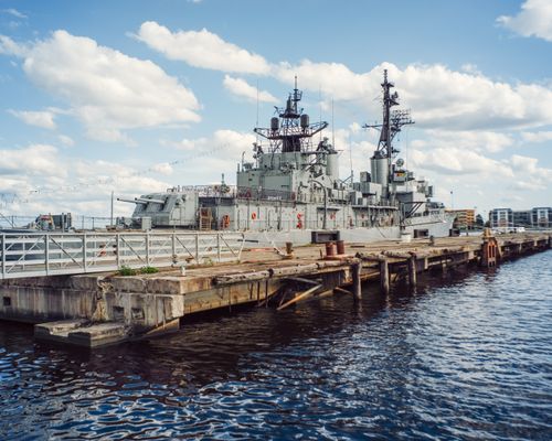 Free A decommissioned warship anchored at a naval museum pier under a clear sky. Stock Photo