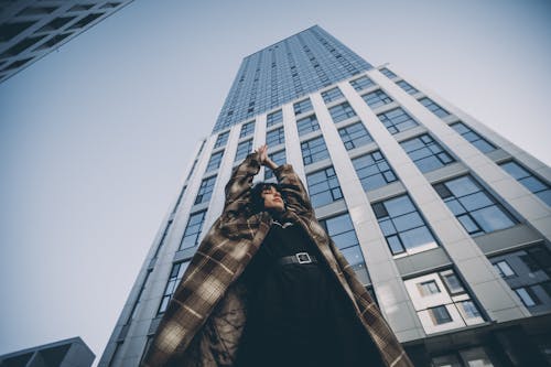 Woman Posing with Arms Raised and Skyscraper behind