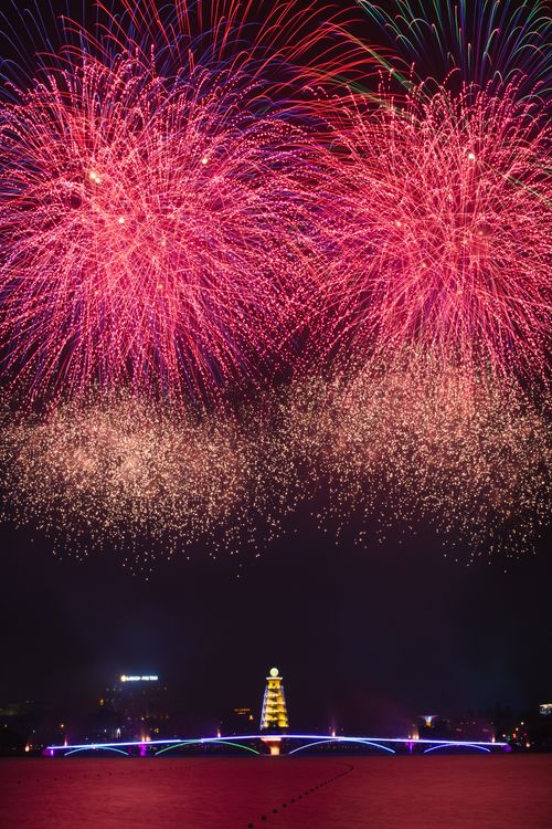 Free Vibrant fireworks light up the night sky above a beautifully illuminated bridge during a festive celebration. Stock Photo