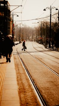 A person crosses a tram track on a city street in İstanbul, Türkiye, during the day.