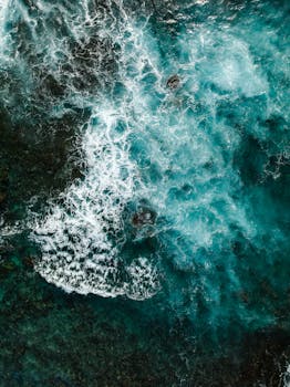 Dynamic aerial view of ocean waves crashing along the rocky coast in Honaunau-Napoopoo, Hawaii.
