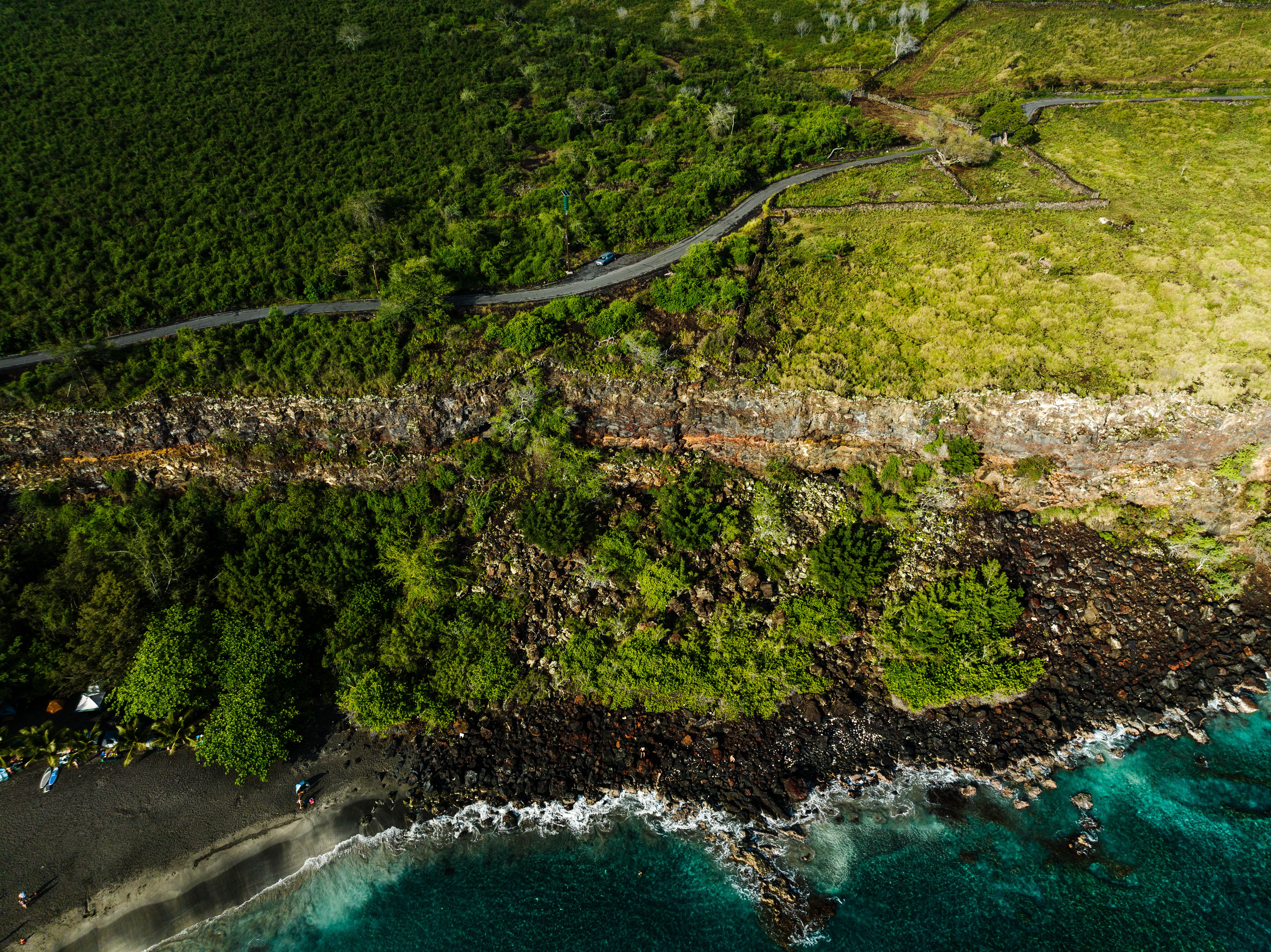 Ultimate Exclusive Landing with Spectacular Big Island Helicopter Tour Review Review 2026 - Drone shot of lush green cliffs and turquoise shore in Honaunau-Napoopoo, Hawaii.