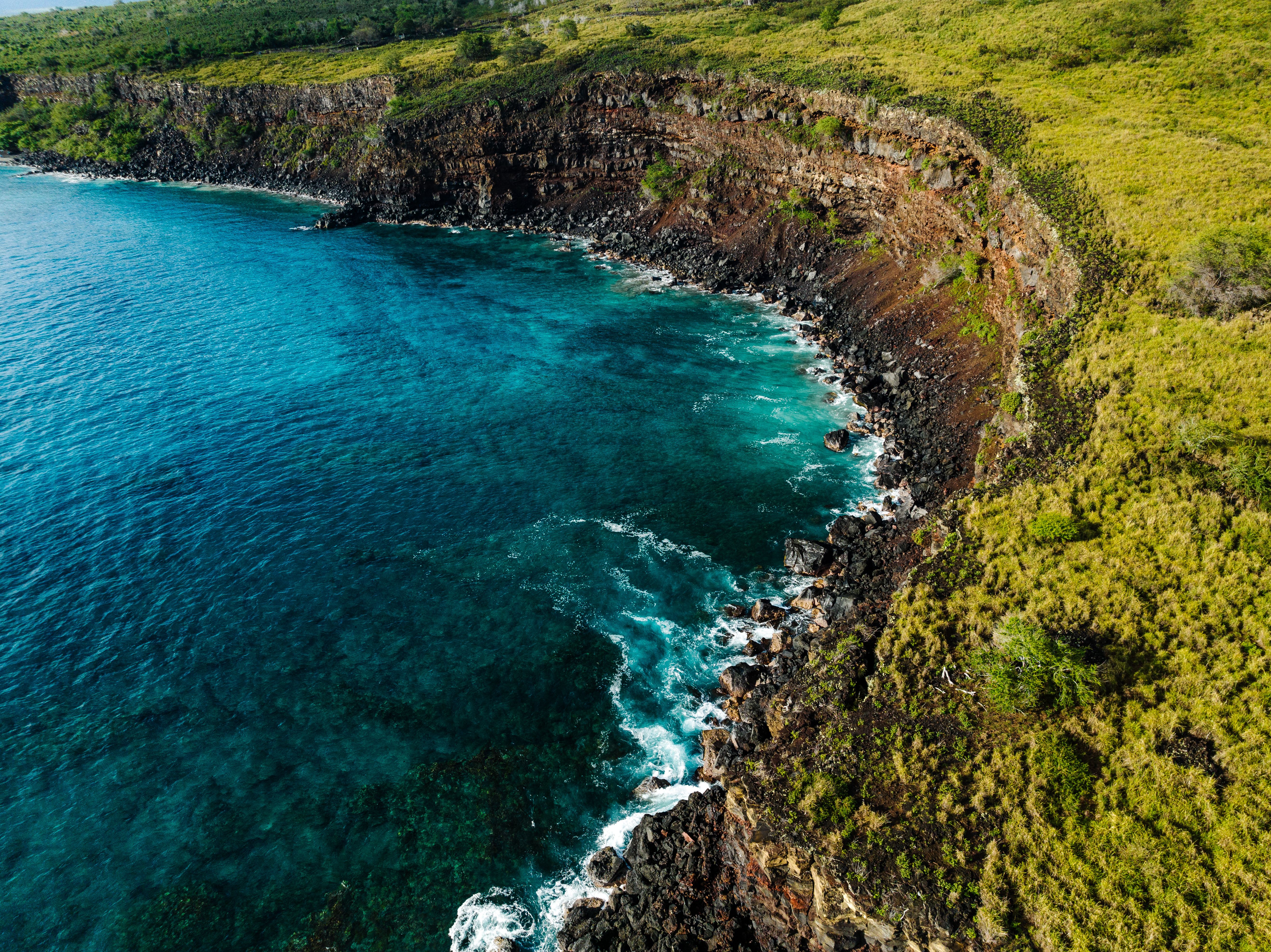 Luxury Helicopter Experience with Hana Rainforest Landing - Aerial view of Honaunau's stunning rocky coastline with vibrant blue waters.