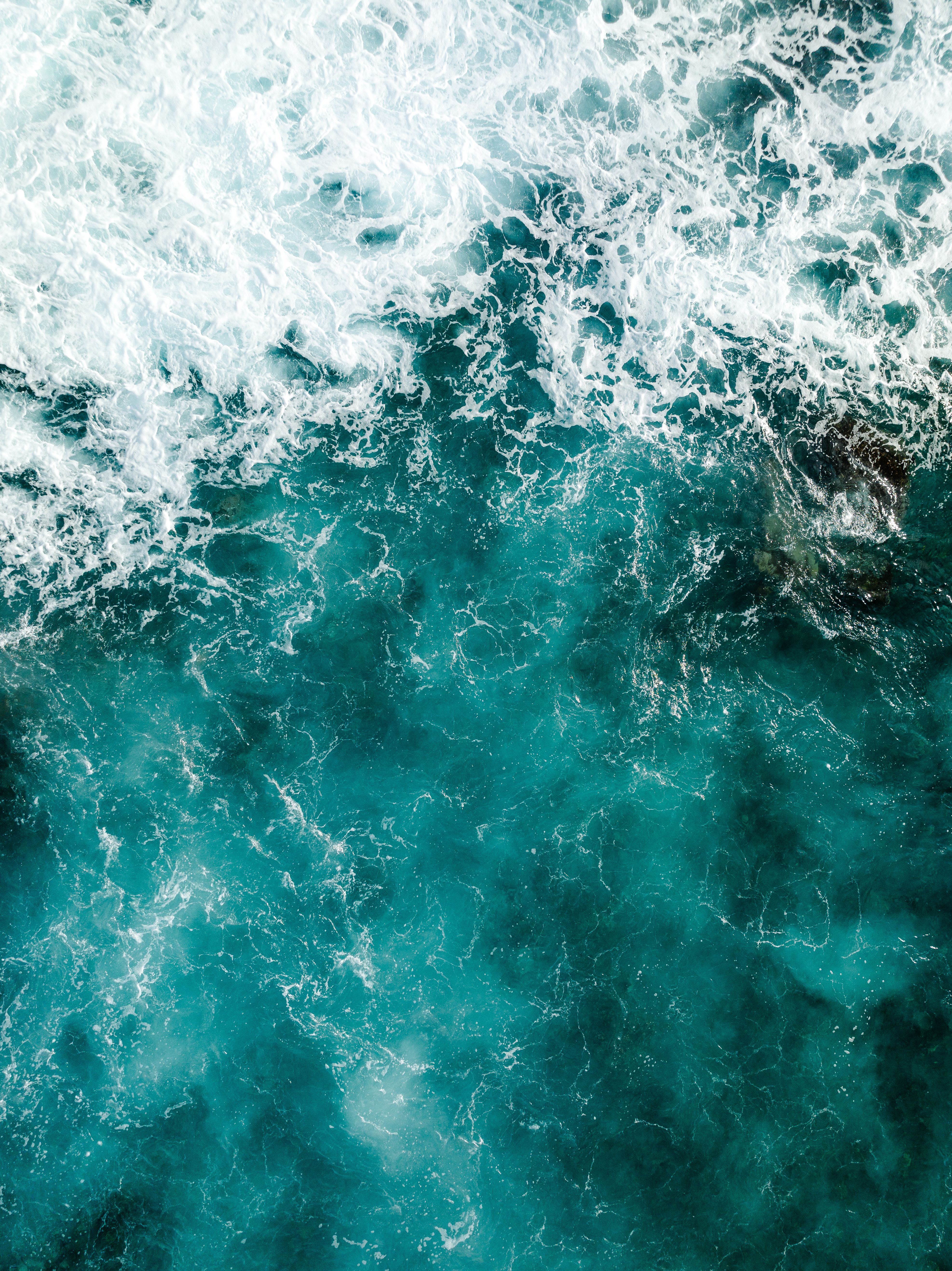 Breathtaking aerial shot of turquoise ocean waves crashing, showcasing nature's power.