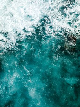 Breathtaking aerial shot of turquoise ocean waves crashing, showcasing nature's power.