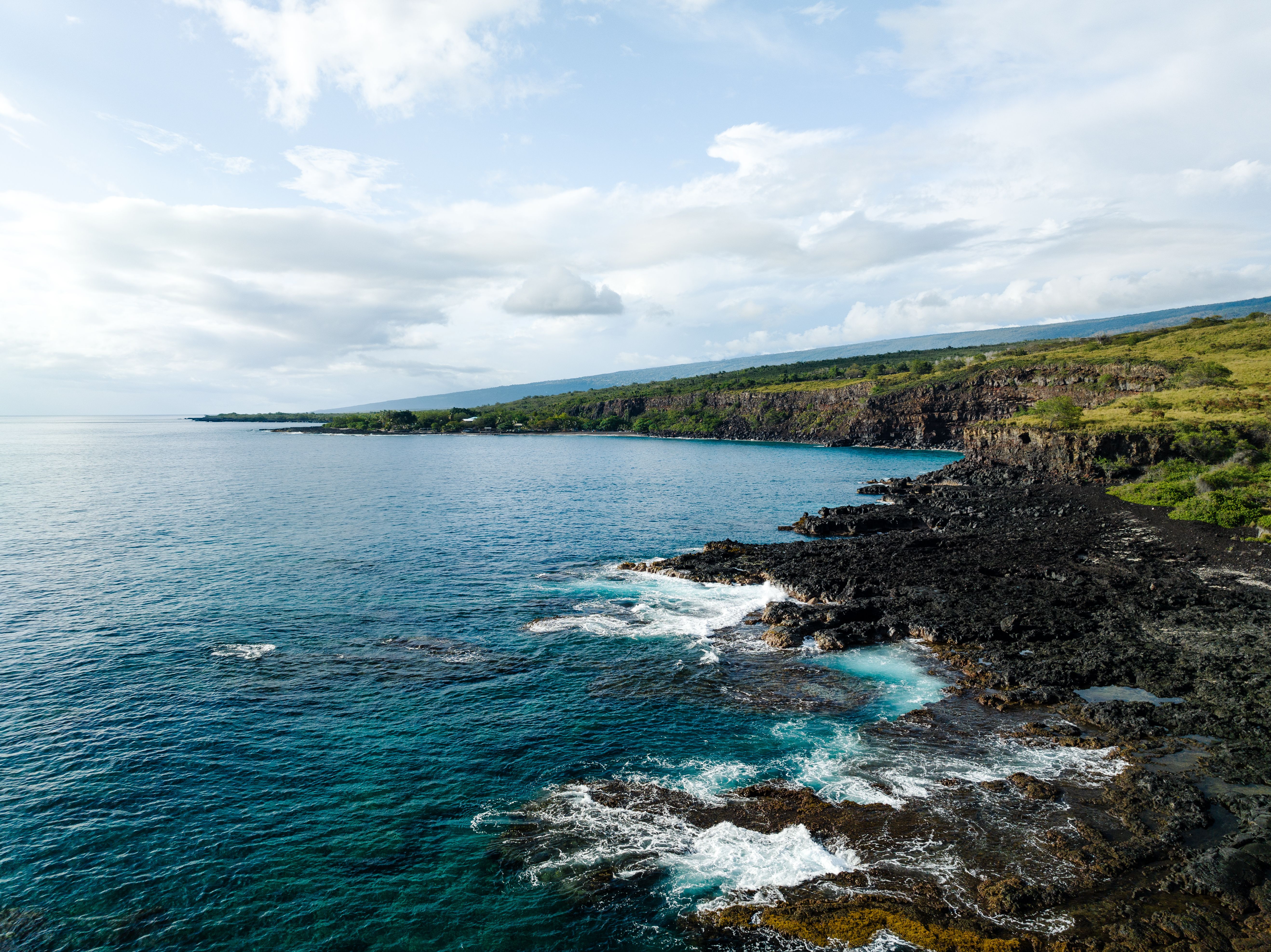 Incredible Big Island Spectacular Helicopter Tour Review: The Ultimate 2-Hour Volcanic Adventure Review 2026 - Breathtaking view of Honaunau-Napoopoo's cliffs and turquoise ocean waves along the Hawaiian coast.