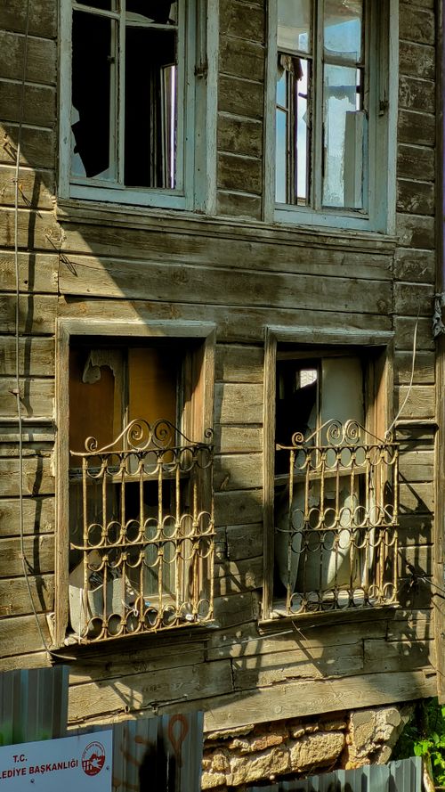 Free Detailed view of a decayed wooden facade with broken windows in sunlight. Stock Photo