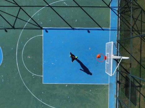 Drone shot capturing a person on a basketball court, showcasing athletic movement from an aerial perspective.