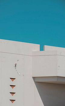 A minimalist architectural facade contrasted with a clear blue sky, showcasing modern design.