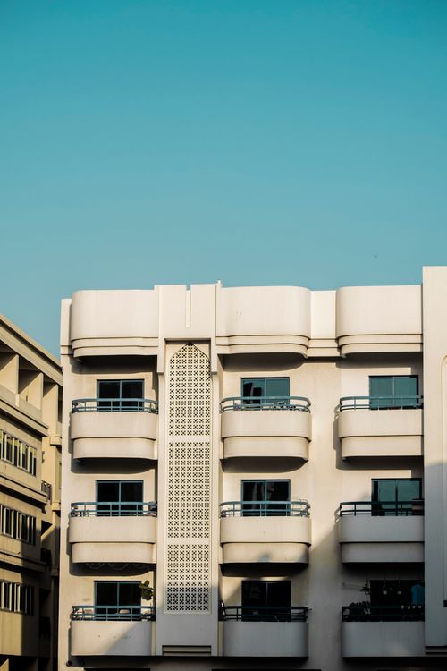 Free A modern apartment building with minimalist architecture under a clear blue sky. Stock Photo