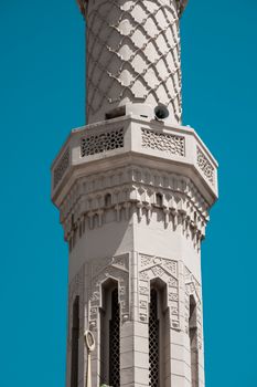 A beautifully detailed minaret under a bright blue sky, showcasing intricate Islamic architecture.