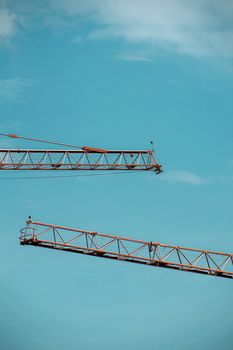A minimalist view of construction cranes set against a clear blue sky, showcasing modern industrial design.