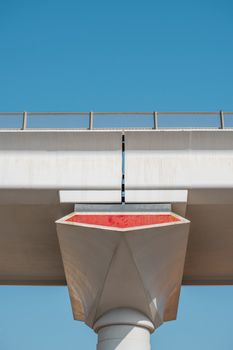 A minimalist composition of an overpass bridge structure contrasted against a clear blue sky.
