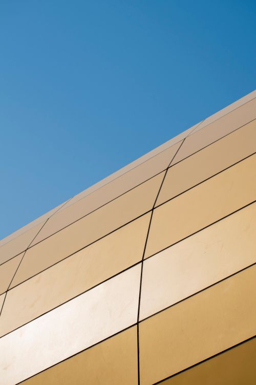 Free A sleek, minimalist architectural facade set against a clear blue sky, capturing modern design. Stock Photo