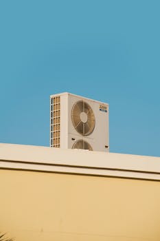 A simple and modern air conditioner unit on a rooftop with a blue sky backdrop in Dubai.