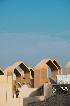 Modern Dubai architecture with unique arches under a clear blue sky.