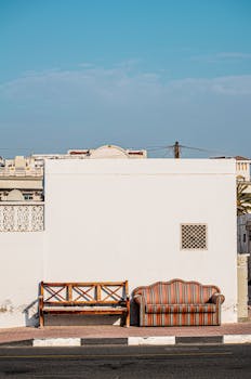 Minimalist outdoor setup with a couch and bench against a wall in Dubai.