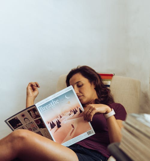 Женщина, лежа на кровати во время чтения журнала в комнате