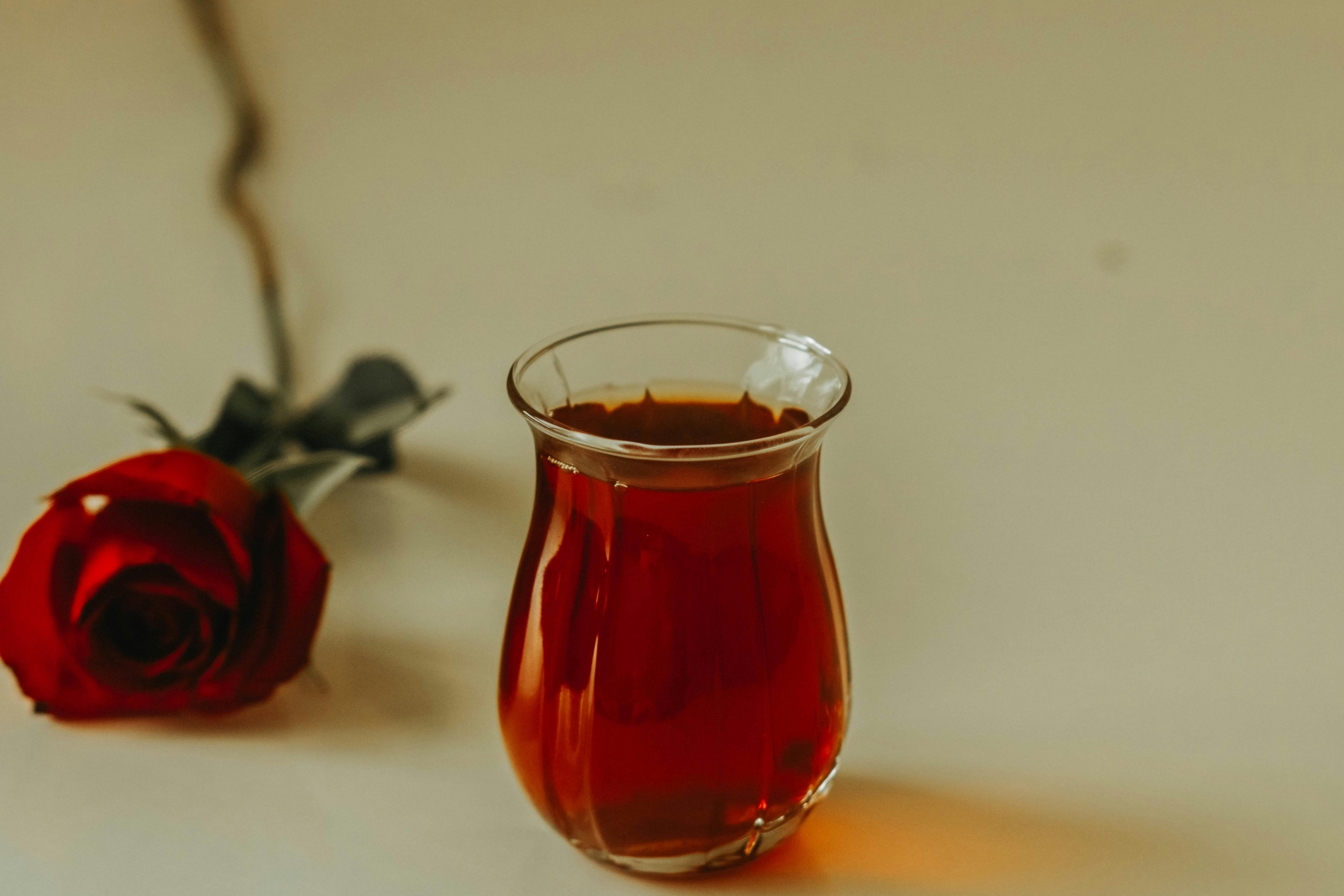 a glass of tea with a rose on the table