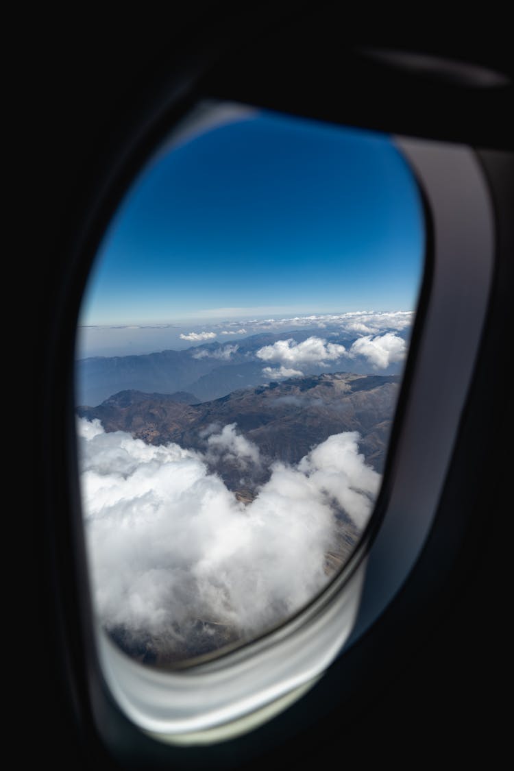 Mountains And Clouds Outside Of An Airplane Window