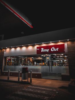 Exterior view of a Time Out convenience store at night, showcasing its lit facade and modern design.
