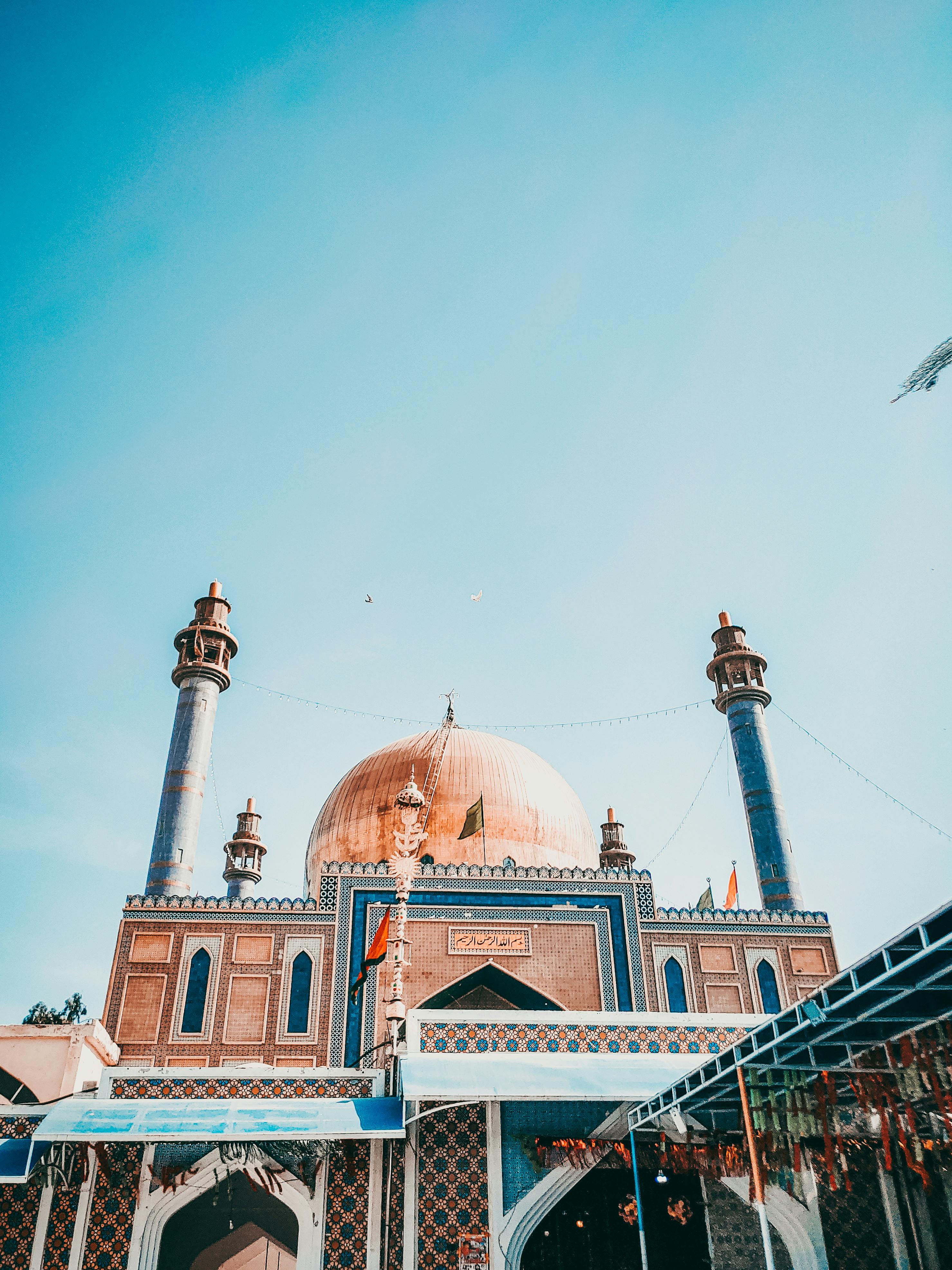Stunning architectural mosque with blue domes and minarets against a clear sky.
