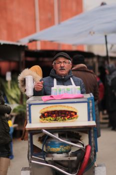 A street vendor in winter attire sells food at an outdoor market, showcasing small business in action.