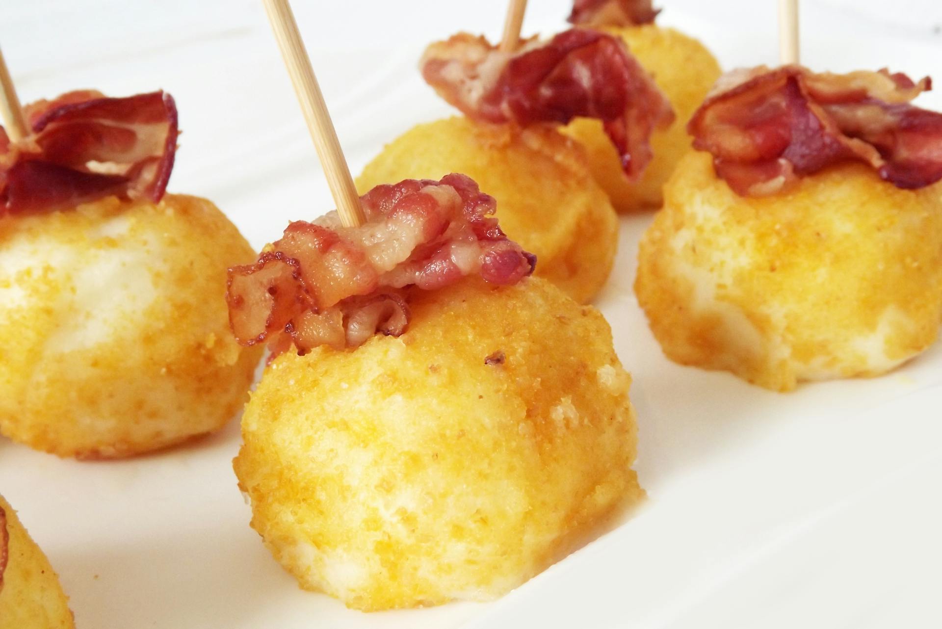 Golden potato croquettes topped with crispy bacon, perfect for appetizers.